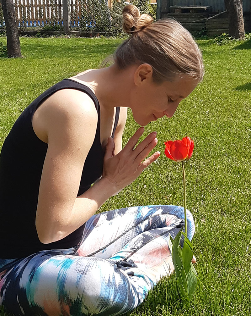 Elisabeth in Yoga-Position vor einer roten Tulpe