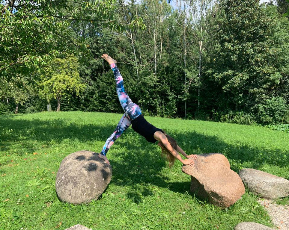 Elisabeth in Yoga-Position zwischen zwei Steinen auf einer Wiese